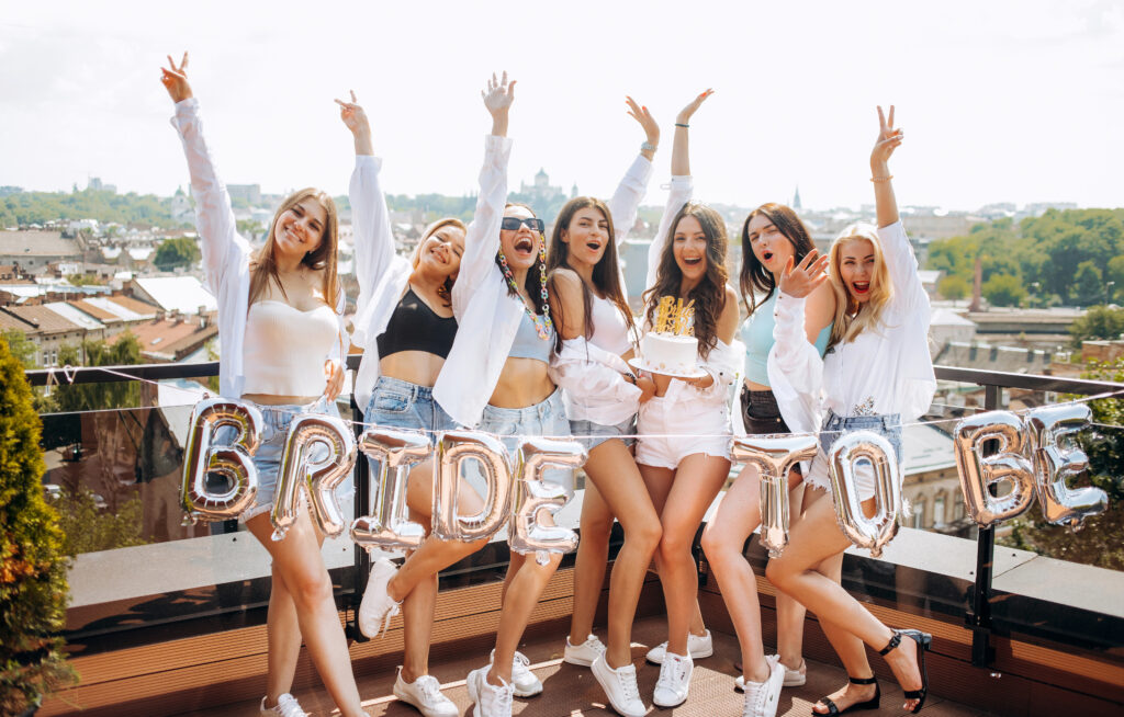 Happy and cheerful group of women friends together dancing and having fun on the rooftop at home. Bachelorette party.